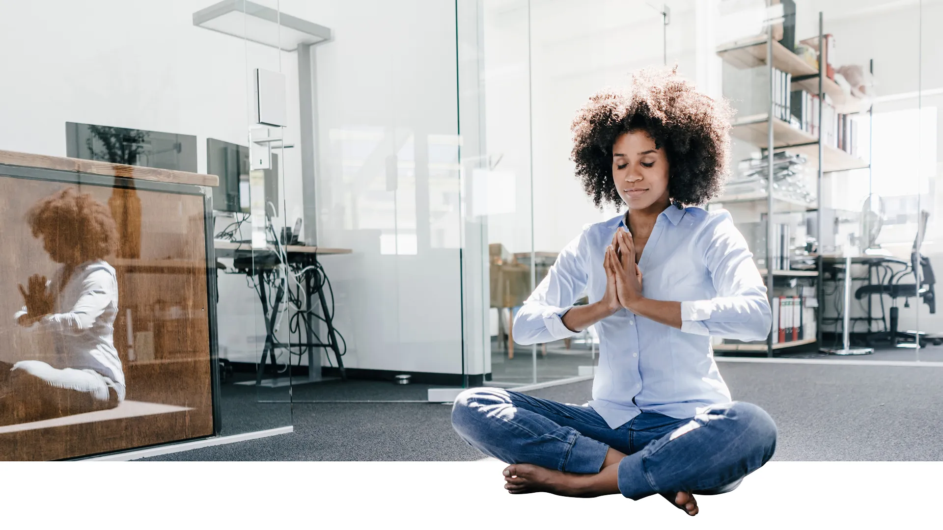 A woman is sitting on the floor with her legs crossed.